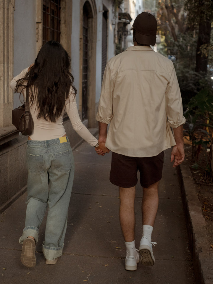 Modelos caminando mientras que la mujer usa un pantalón tipo denim ,bolso café y body.