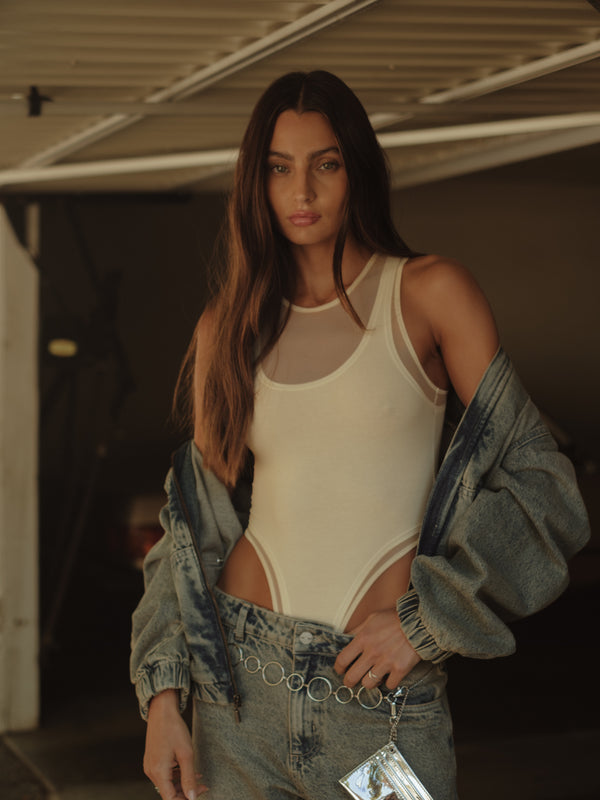 Vista frontal modelo con bodie crudo con transparencias y chaqueta.