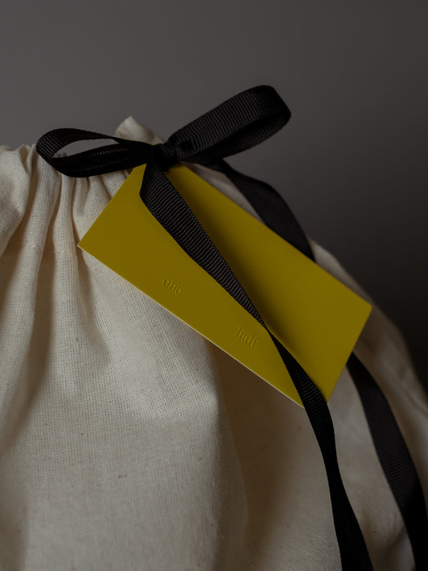 Detalle de moño negro con tarjeta amarilla de bolsa de regalo de tela. 