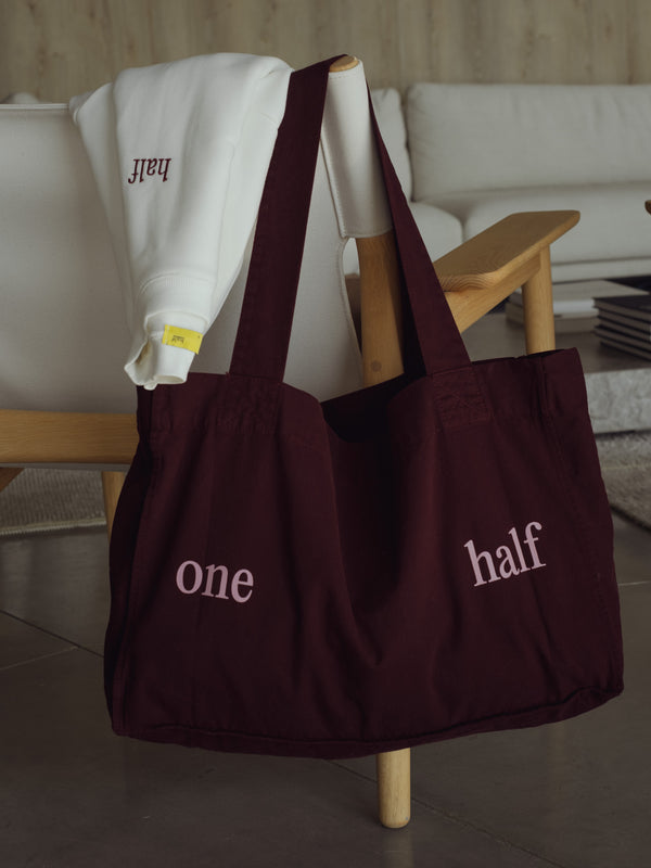Vista frontal tote bag color vino con estampado "One Half" rosado.