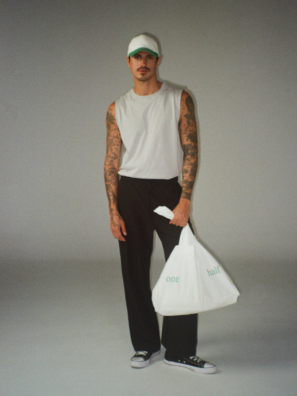 modelo usando tank gris con pantalón negro y tote bag crudo.