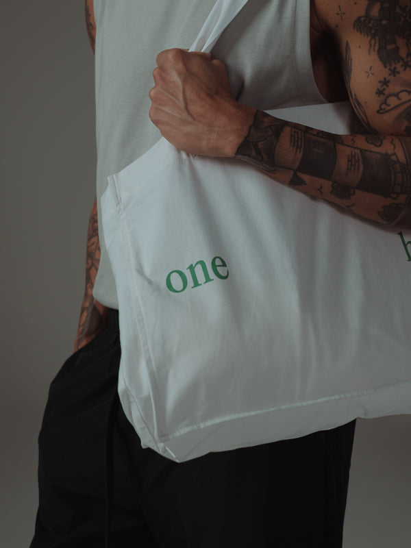 Vista a frontal de tote bag crudo con estampado verde "One Half"