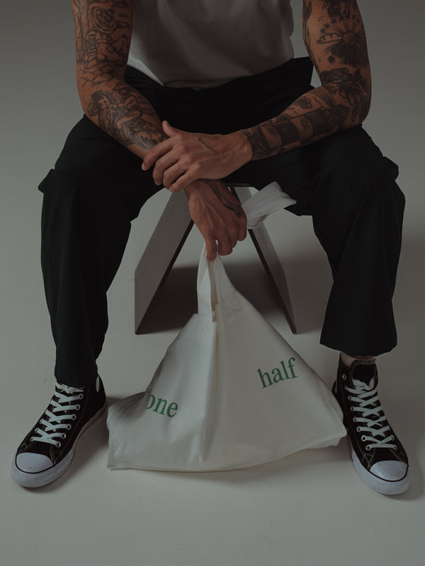 Modelo sentado con tote bag crudo con estampado verde.