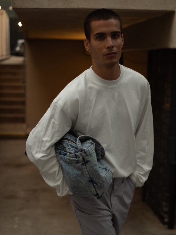 Modelo con buzo crudo y jean gris sosteniendo tote bag denim azul.