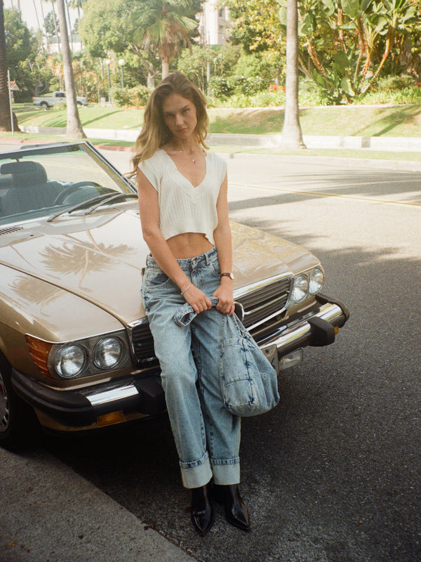 Modelo en la calle usando chaleco crema con jean y tote bag denim.