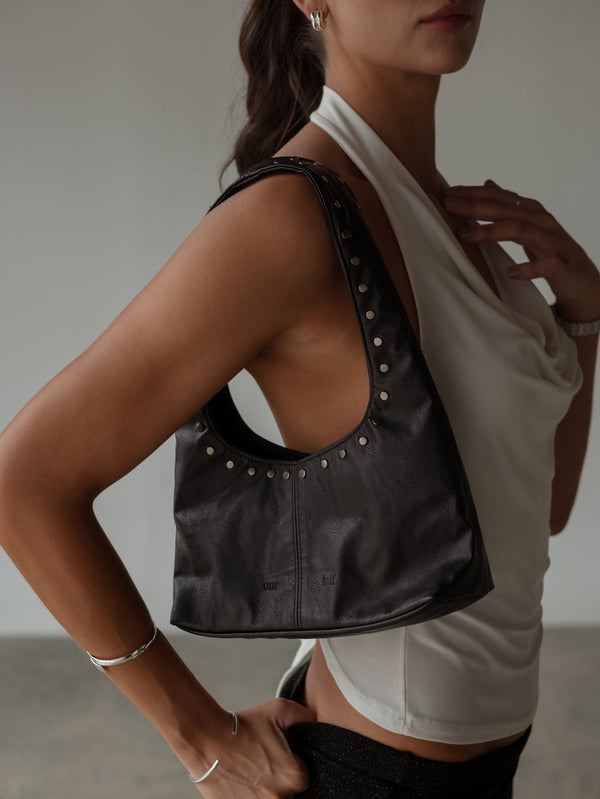 Modelo con mini bolso de cuero sintético y taches en el hombro.