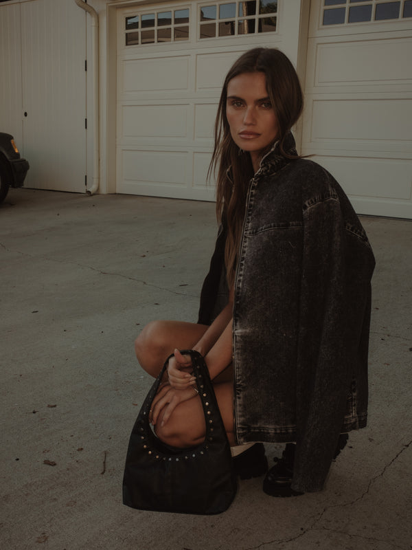Modelo con chaqueta negra y mini bolso negro de taches metálicos. 