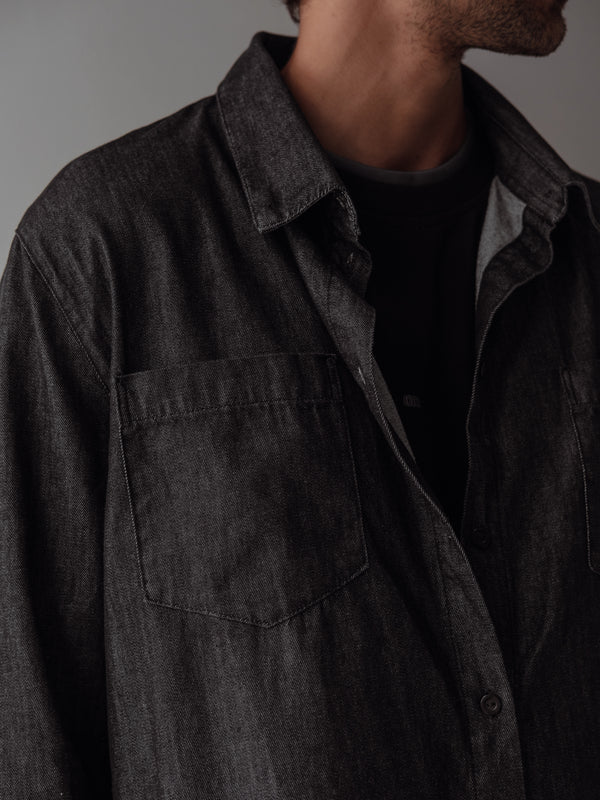 Vista a detalle camisa negra con lavado vintage, botones, bolsillo y cuello. 