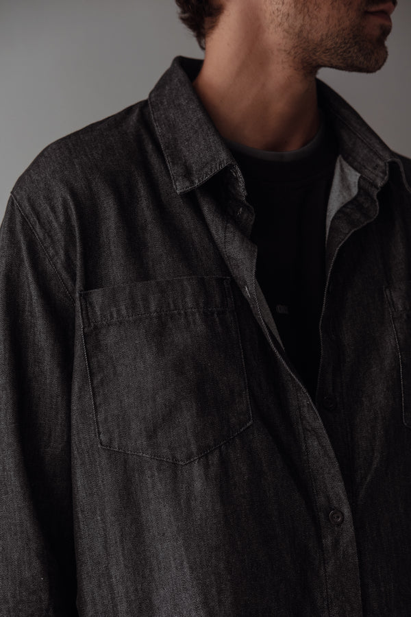 Vista a detalle camisa negra con lavado vintage, botones, bolsillo y cuello. 