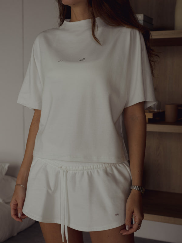 Vista frontal modelo con mini falda y camiseta ancha crudo.