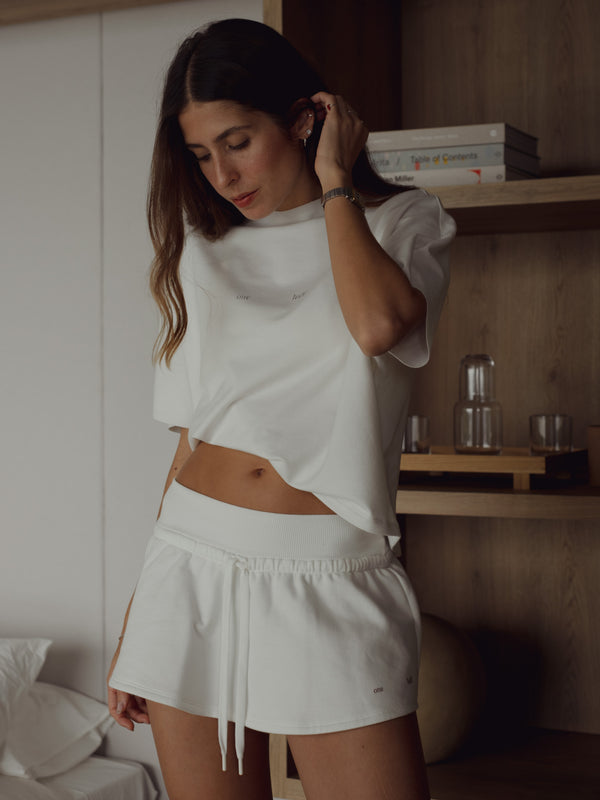 Modelo usando camiseta amplia crudo para mujer con mini falda.