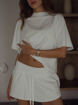 Modelo usando camiseta crudo cuello redondo con falda crudo.