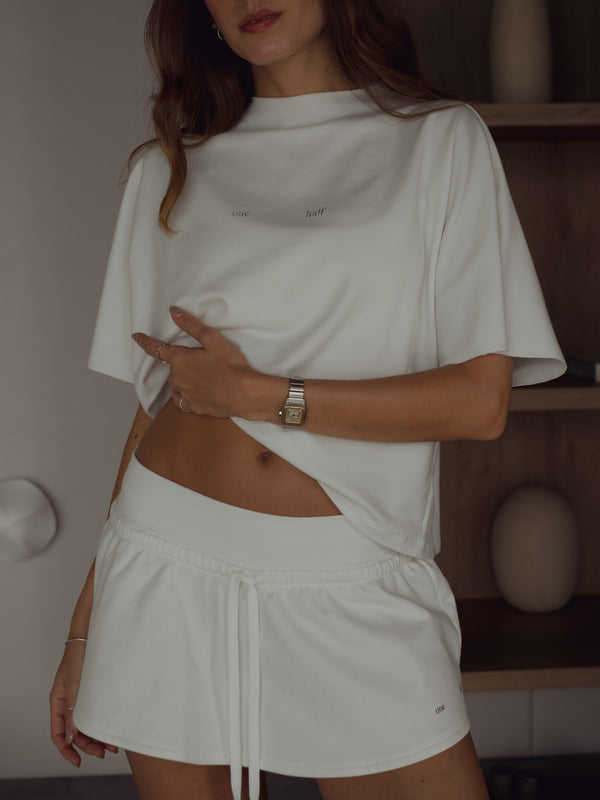 Modelo usando camiseta crudo cuello redondo con falda crudo.