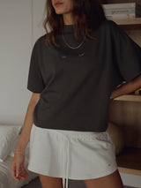 Vista frontal modelo usando camiseta gris oscuro con mini falda crudo.
