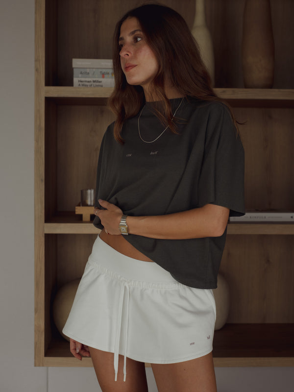 Modelo con camiseta gris oscuro con mini falda crudo.