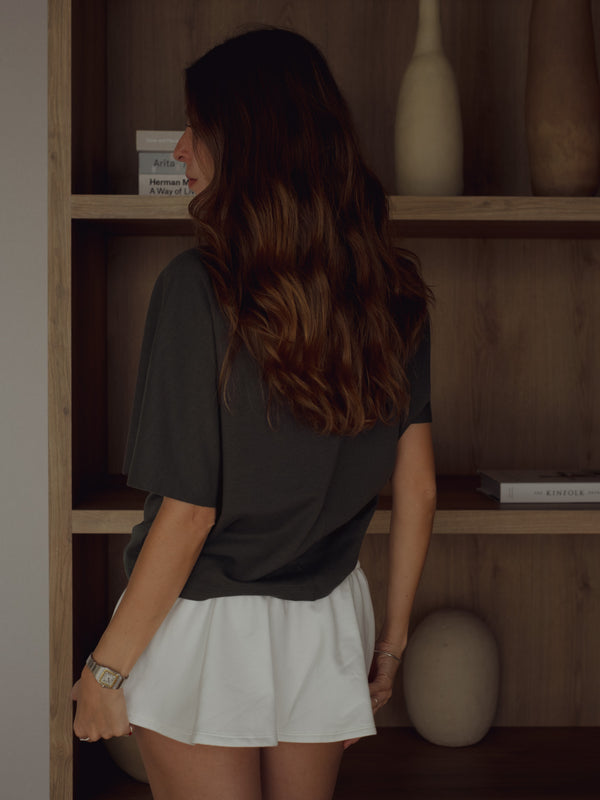 Vista posterior modelo usando mini falda crudo con camiseta gris.