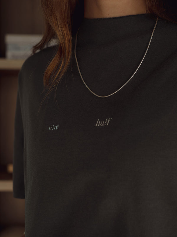 Vista frontal a detalle estampado "One Half" de camiseta gris.