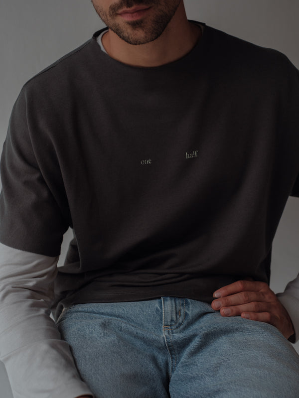 Vista frontal camiseta gris con mangas al corte y estampado "one Half" centrado.
