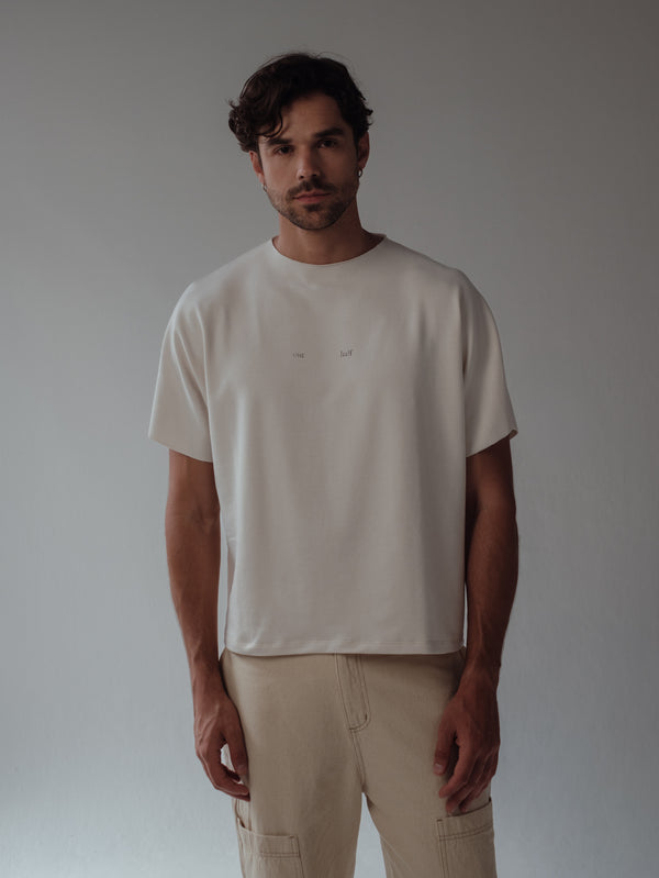 Modelo usando camiseta boxy crema y jean crema. 