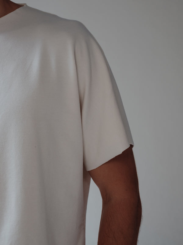 Vista a detalle manga al corte de camiseta crema tipo boxy. 