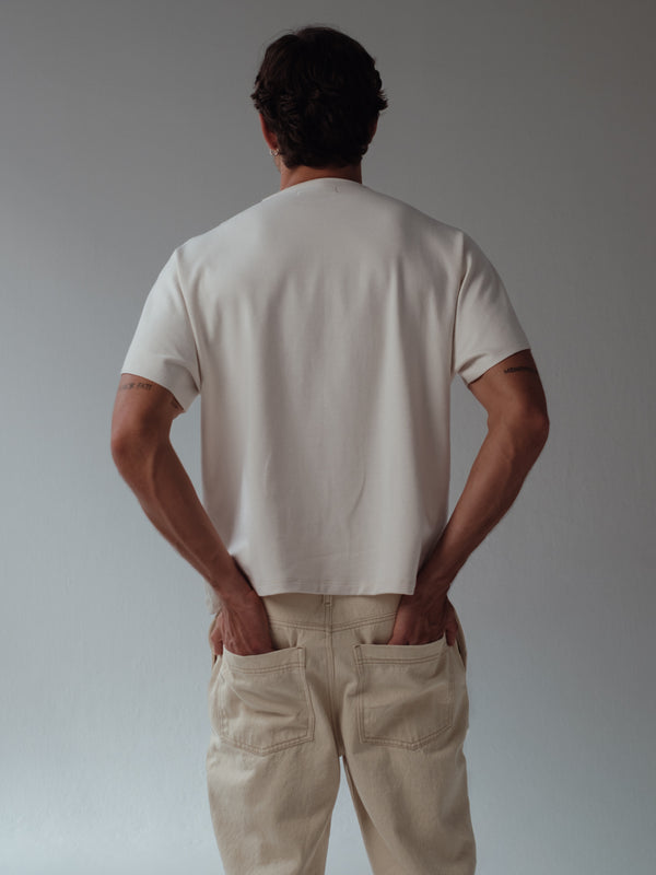 Vista posterior de camiseta boxy color crema para hombre. 