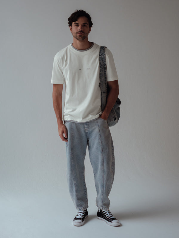 Modelo usando camiseta crudo con jean azul claro ancho y tote bag denim. 