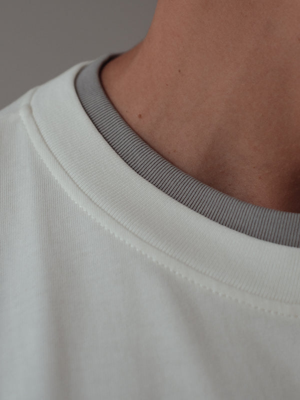 Vista a detalle cuello doble contraste gris de camiseta crudo. 