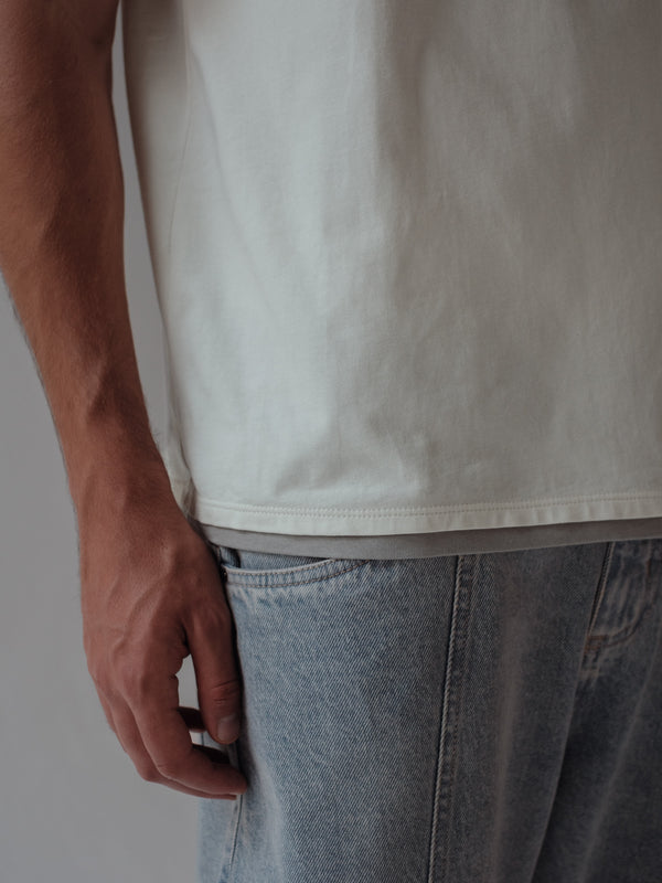 Vista a detalle ruedo doble gris de camiseta crudo.