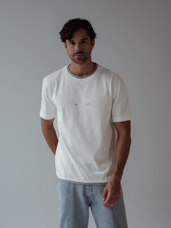 Modelo usando camiseta crudo con detalles gris en cuello y ruedo.