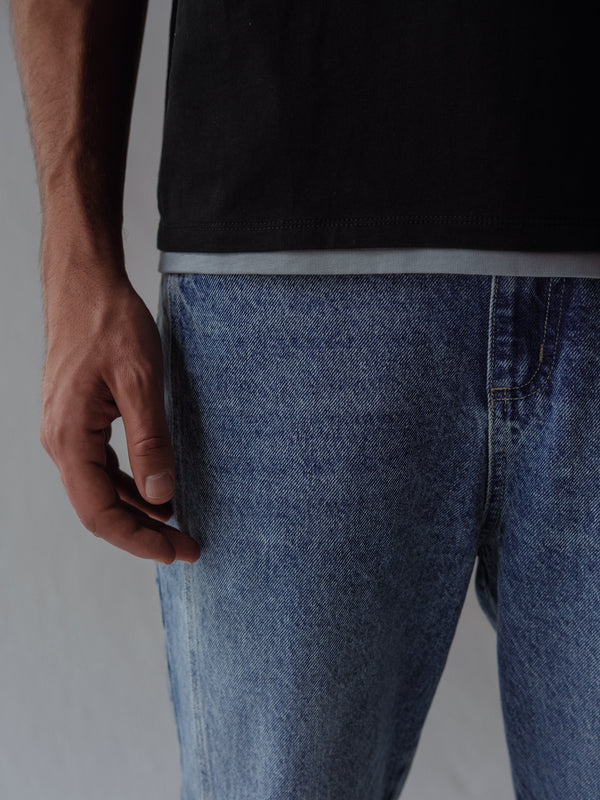 Vista a detalle ruedo doble gris de camiseta negra fit regular.