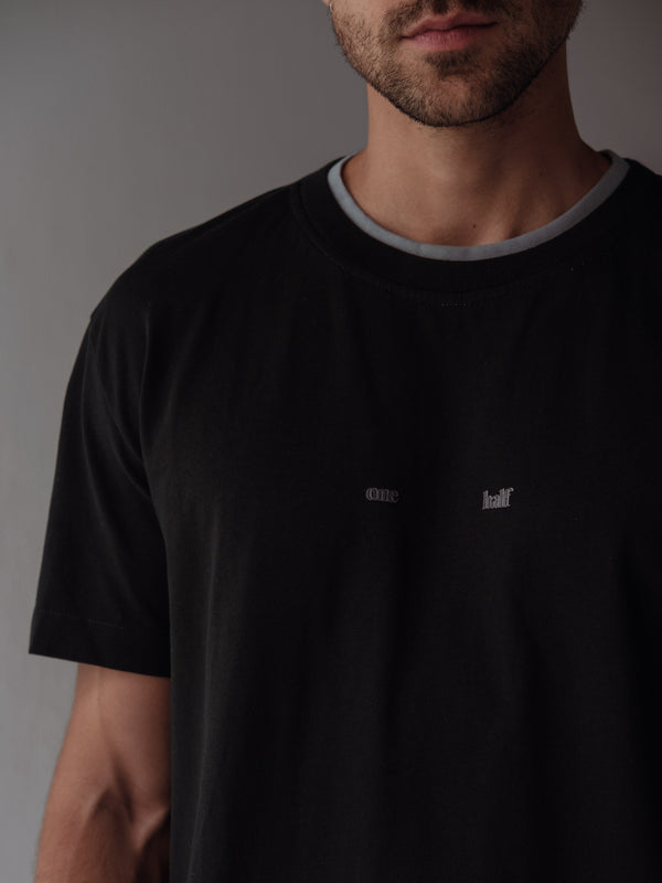 Vista frontal a detalle de camiseta negra con estampado centrado "One Half".