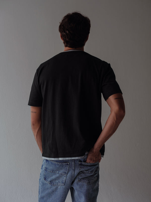 Vista posterior modelo usando camiseta negra con detalles en gris.