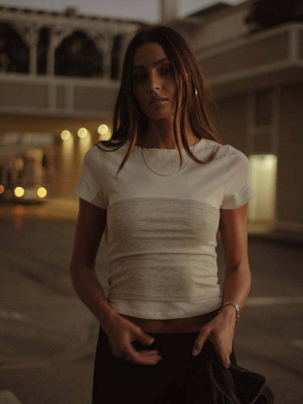 Vista frontal modelo con camiseta crudo con detalle strapless gris.