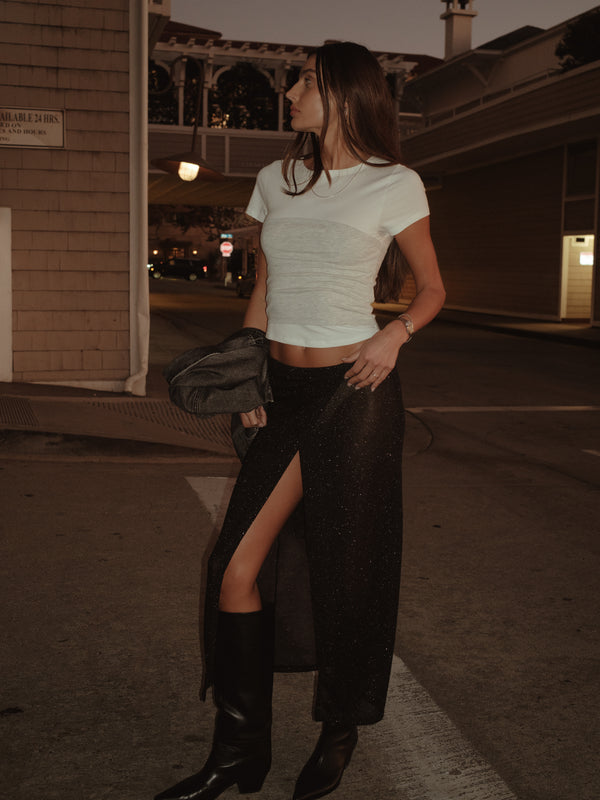 Modelo con camiseta crudo y gris tipo strapless con falda y botas.