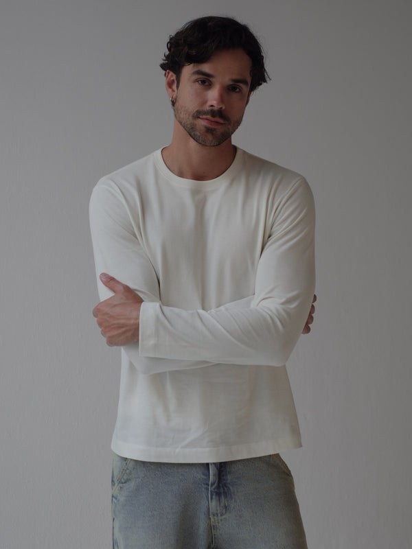 Modelo con los brazos cruzados usando camiseta manga larga crudo.