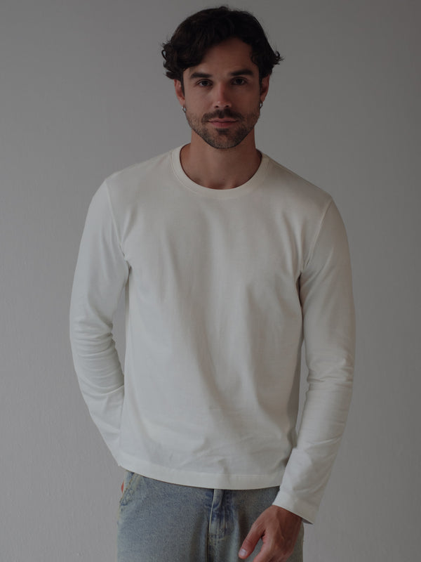 Modelo usando camiseta manga larga crudo cuello redondo.