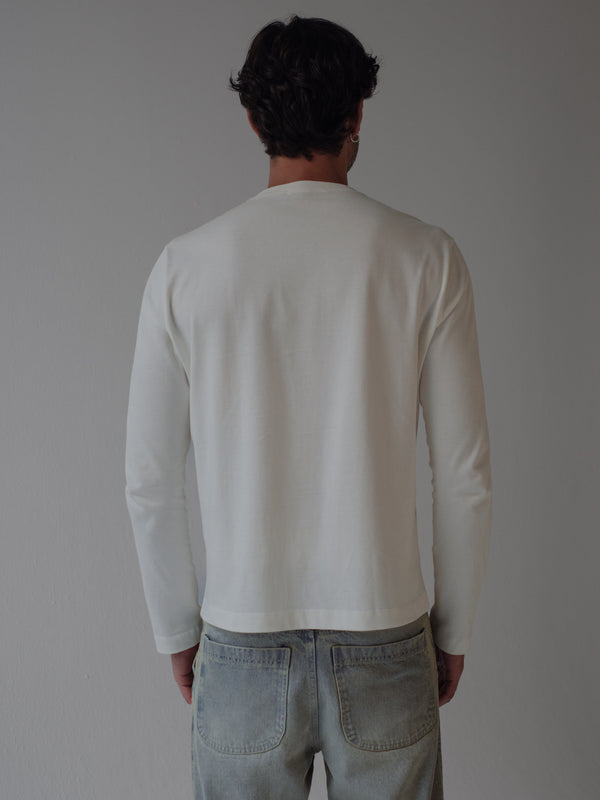 Modelo de espalda usando camiseta manga larga crudo con jean azul ahumado.