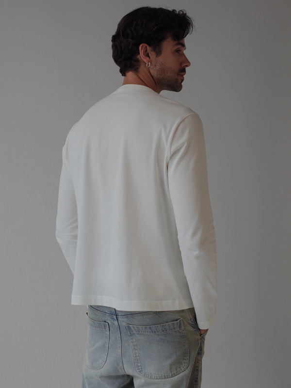 Vista posterior de modelo usando camiseta manga larga color crudo.