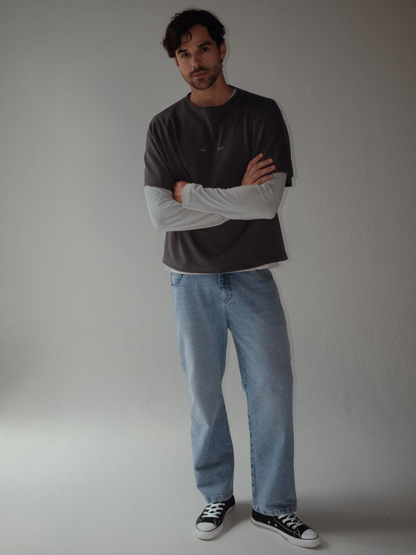 Modelo con jean clásico azul y camiseta gris tipo layering con camiseta manga larga gris claro.
