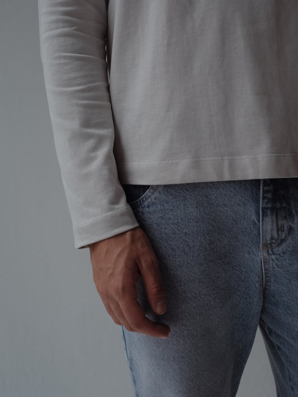 Vista a detalle de ruedo y manga de camiseta gris. 