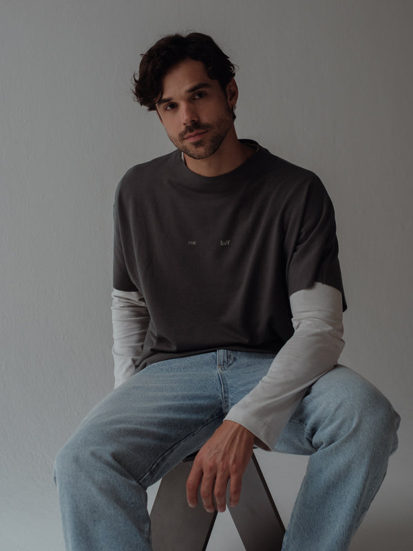 Modelo usando camiseta manga larga gris y camiseta manga corta por encima gris oscuro.