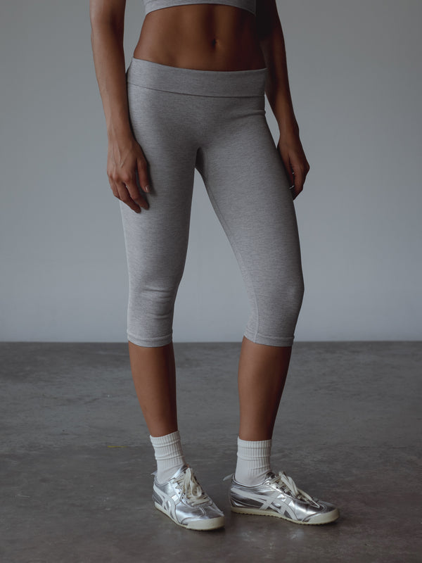 Modelo usando capri deportivo gris, medias midi blancas y tenis plateados.
