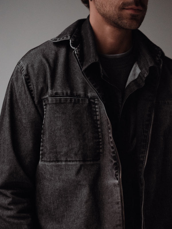 Vista frontal a detalle de cremallera de chaqueta negra con lavado vintage. 