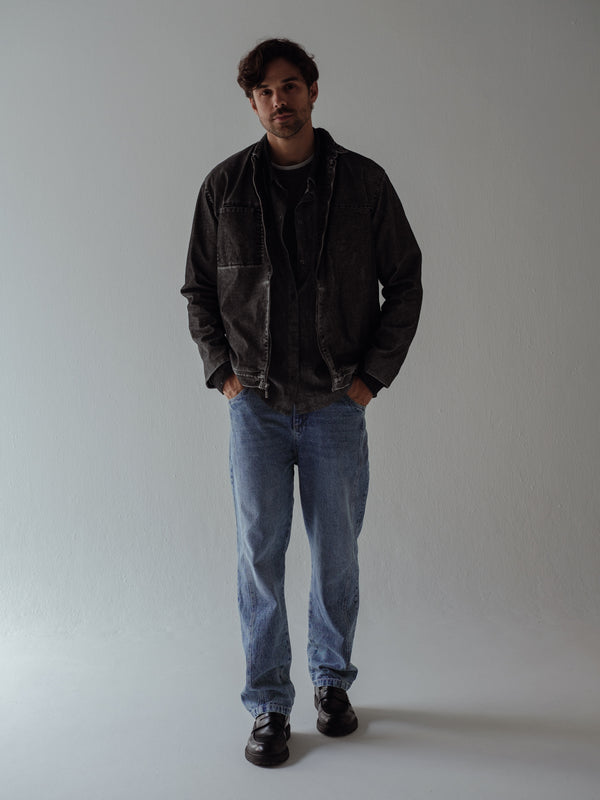 Modelo usando chaqueta negra vintage con jean azul claro y zapatos negros.