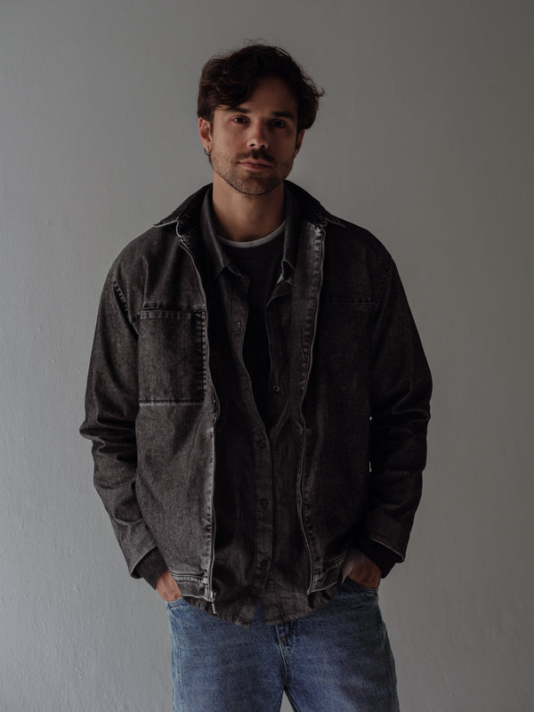 Modelo usando camiseta, camisa y chaqueta negra tipo layering.