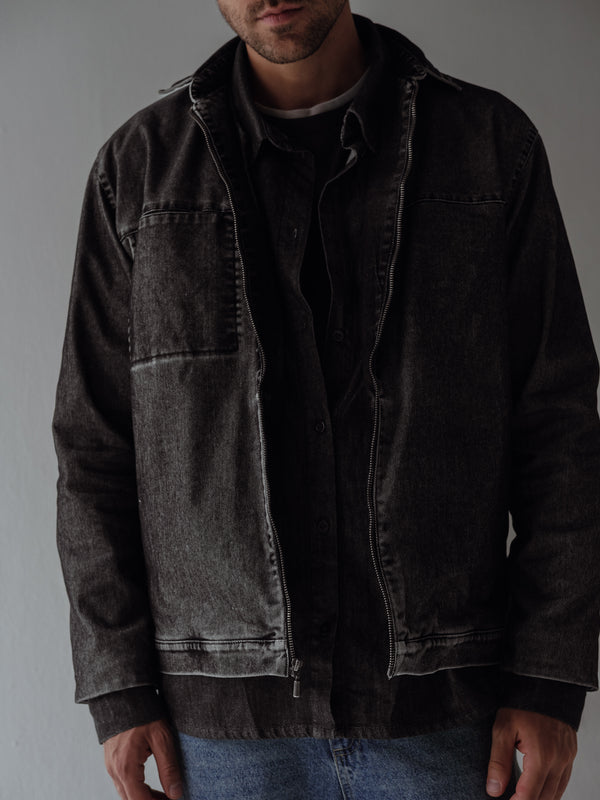 Vista frontal de chaqueta negra vintage con cierre y lavado vintage.