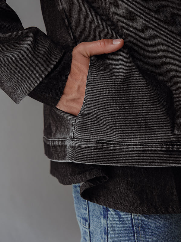 Vista a detalle de bolsillos laterales de chaqueta negra con lavado vintage. 