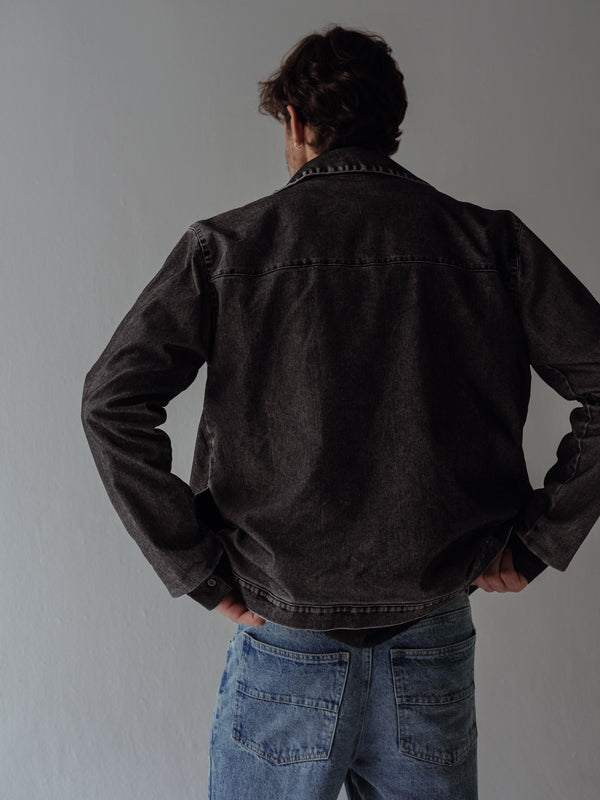 Vista posterior de chaqueta negra vintage con bolsillos y cremallera. 