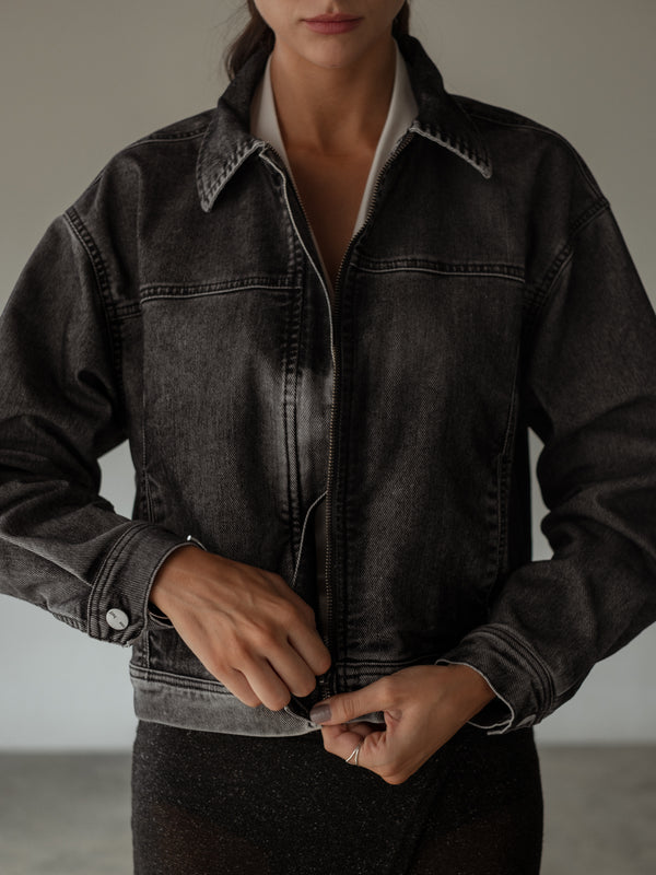 Vista frontal de modelo con chaqueta negra cuello camisero con cremallera.