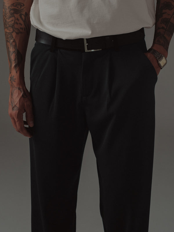 Vista frontal modelo usando pantalón negro con cinturón de hebilla plata.